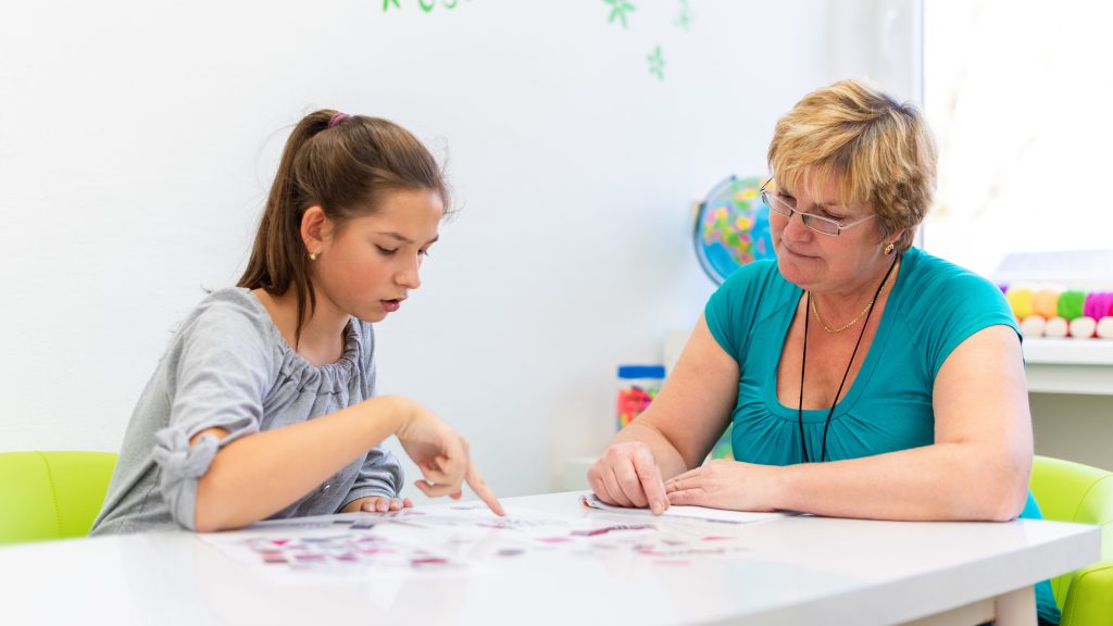 Female therapist working with a teenage girl with learning difficulties to master logical tests.
